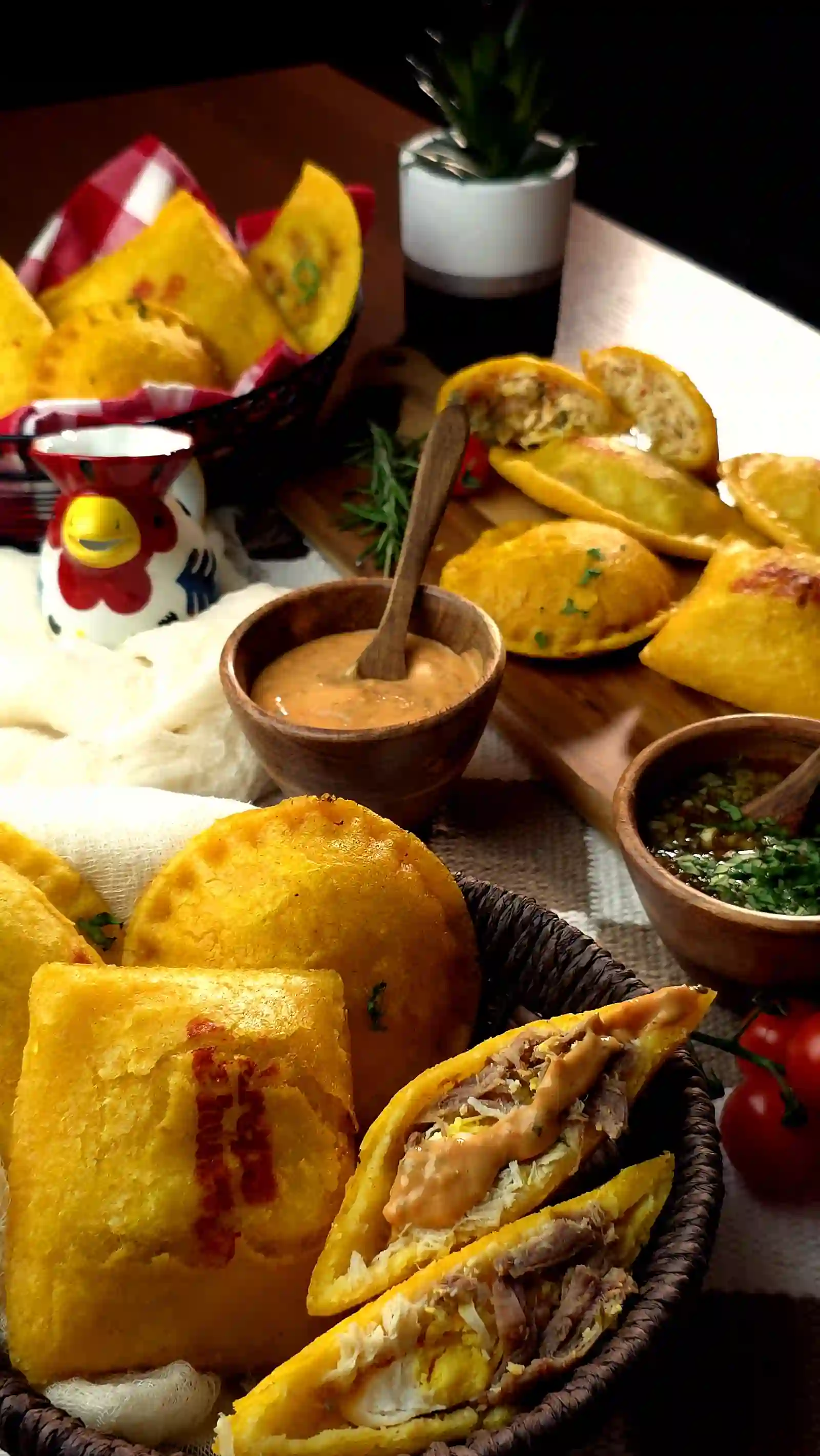 Una mesa de empanadas y panzerottis colombianos con ají y salsas